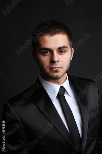 Photo: Handsome young man in suit on dark background Handsome young man in suit on dark background