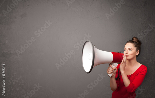 Photo: Girl shouting into megaphone on copy space background Girl shouting into megaphone on copy space background