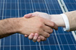 A handshake in front of solar energy panels A handshake in front of solar energy panels