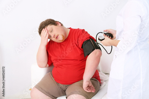 Photo: Doctor examining patient obesity on light background Doctor examining patient obesity on light background