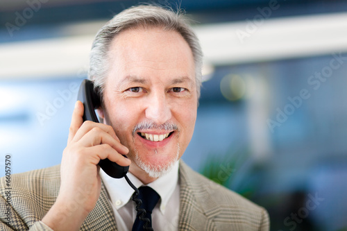 Photo: Portrait of a mature businessman speaking at the phone Portrait of a mature businessman speaking at the phone