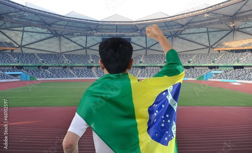 Photo: man holding the flag of Brazil celebrates on the stadium man holding the flag of Brazil celebrates on the stadium