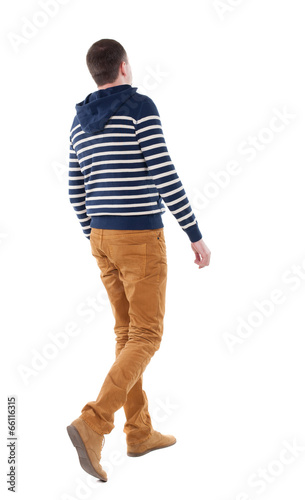 Photo: Back view of walking handsome man in jeans and striped sweater. Back view of walking handsome man in jeans and striped sweater.