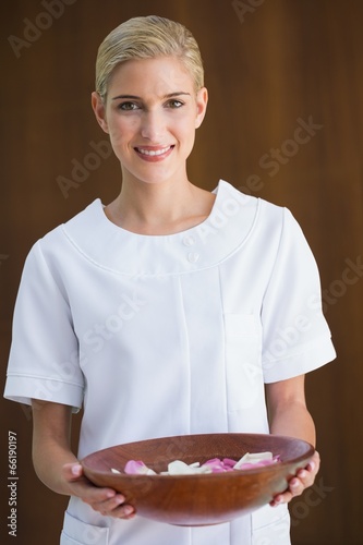 Photo: Smiling beauty therapist holding bowl of rose petals Smiling beauty therapist holding bowl of rose petals