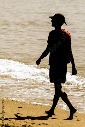 Photo: Hombre caminando por la orilla de la playa Hombre caminando por la orilla de la playa