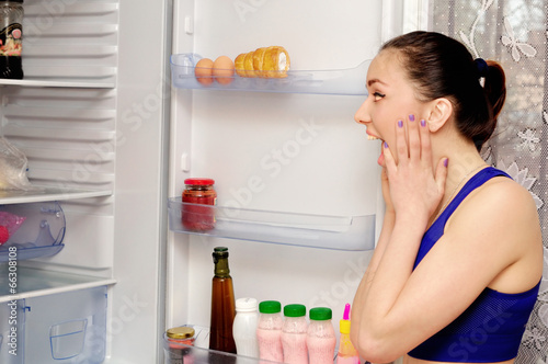 Photo: Girl in horror at the open refrigerator Girl in horror at the open refrigerator