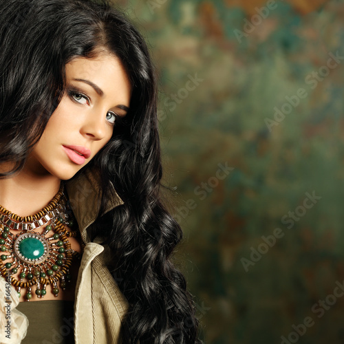 Photo: Beautiful fashion woman with curly hair and stage makeup on back Beautiful fashion woman with curly hair and stage makeup on back
