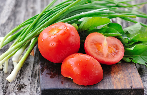Photo: Tomatoes with onions and arugula on a wooden board Tomatoes with onions and arugula on a wooden board