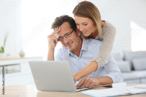 Photo: Woman trying to relax worried husband in front of laptop Woman trying to relax worried husband in front of laptop