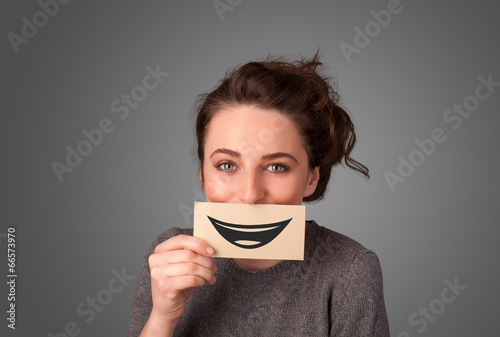 Photo: Happy pretty woman holding card with funny smiley Happy pretty woman holding card with funny smiley