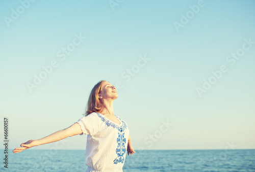 Photo: happy young woman open her arms to the sky and sea happy young woman open her arms to the sky and sea