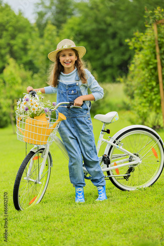 Photo: Cycling - girl with bicycle in the garden Cycling - girl with bicycle in the garden