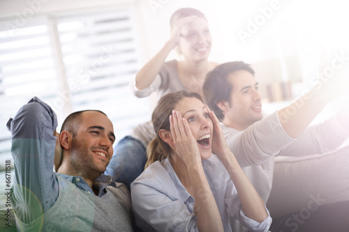 Photo: Cheerful group of friends watching football game on tv Cheerful group of friends watching football game on tv
