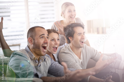 Photo: Cheerful group of friends watching football game on tv Cheerful group of friends watching football game on tv