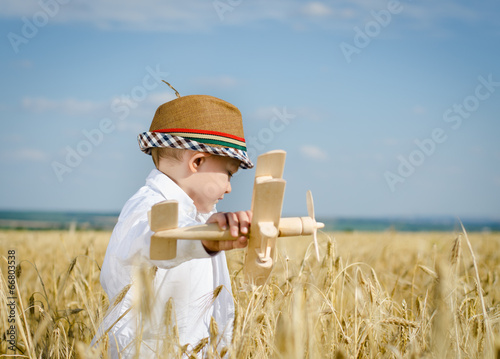 Photo: Trendy young boy playing in a field with a plane Trendy young boy playing in a field with a plane