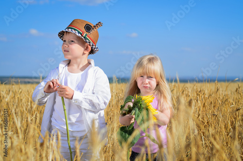 Photo: Little girl and boy examining yellow sunflowers Little girl and boy examining yellow sunflowers