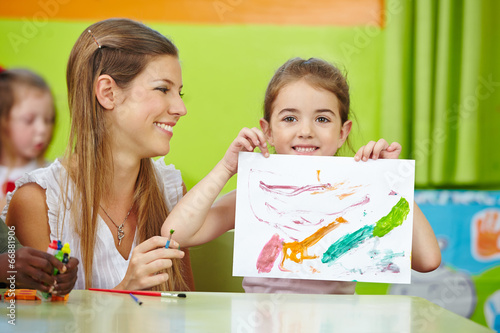 Photo: Girl showing self drawn painting in kindergarten Girl showing self drawn painting in kindergarten
