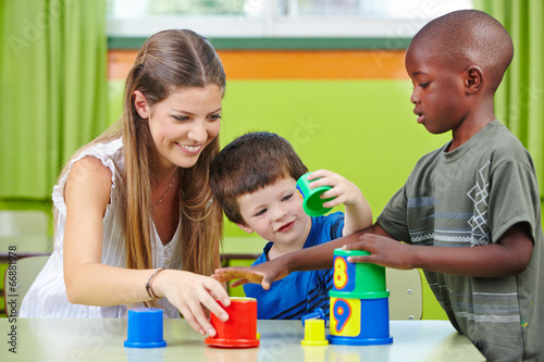 Photo: Nursery teacher building tower with children Nursery teacher building tower with children