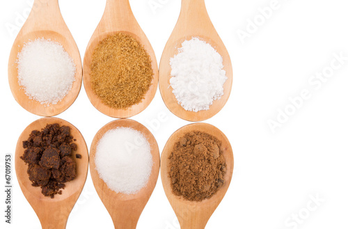 Photo: Various type of sugar on wooden spoon over white background Various type of sugar on wooden spoon over white background