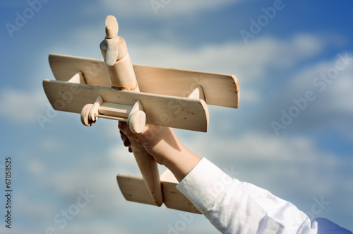 Photo: Hand of a child playing with a wooden airplane toy Hand of a child playing with a wooden airplane toy