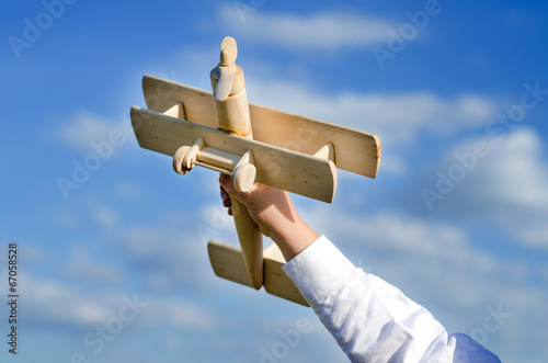Photo: Hand of a child playing with a wooden airplane toy Hand of a child playing with a wooden airplane toy