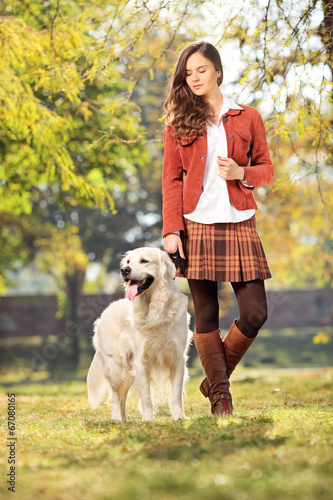 Photo: Beautiful girl walking her dog in park Beautiful girl walking her dog in park