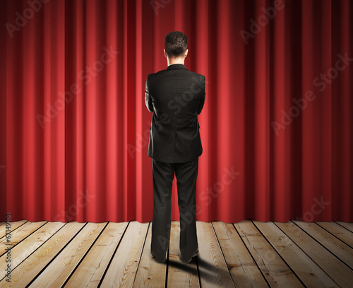 Photo: businessman looking to red curtains businessman looking to red curtains