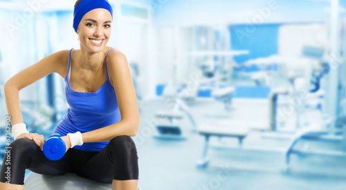 Photo: Young happy woman doing fitness exercise, at gym Young happy woman doing fitness exercise, at gym
