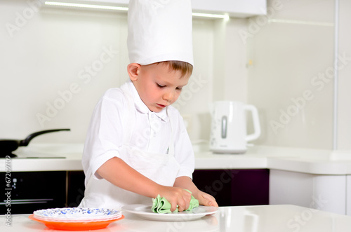 Photo: Little boy chef cleaning his plates while cooking Little boy chef cleaning his plates while cooking