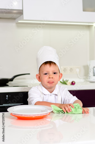 Photo: Little boy chef cleaning his plates while cooking Little boy chef cleaning his plates while cooking