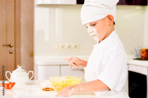 Photo: Serious little chef consulting his recipe book Serious little chef consulting his recipe book