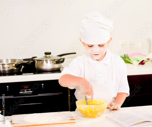Photo: Cute little boy baking in his kitchen at home Cute little boy baking in his kitchen at home