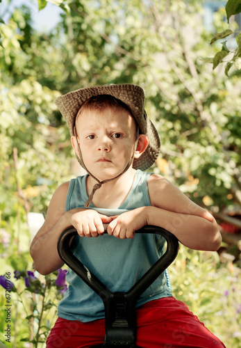 Photo: Thoughtful young boy sitting in a country garden Thoughtful young boy sitting in a country garden