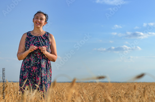 Photo: Smiling happy woman in a golden field of wheat Smiling happy woman in a golden field of wheat