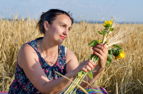 Photo: Laughing woman holding flowers in a wheat field Laughing woman holding flowers in a wheat field
