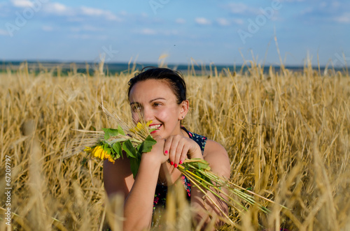 Photo: Laughing woman holding flowers in a wheat field Laughing woman holding flowers in a wheat field