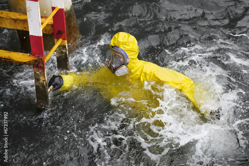 Photo: worker in protective suit in sea reaching ladder worker in protective suit in sea reaching ladder