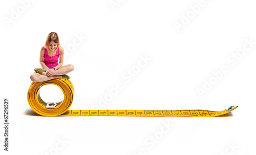Photo: Young pretty girl looking down on tape measure Young pretty girl looking down on tape measure