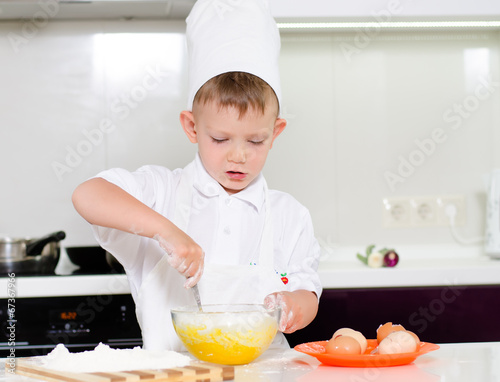 Photo: Young boy baking whipping eggs Young boy baking whipping eggs