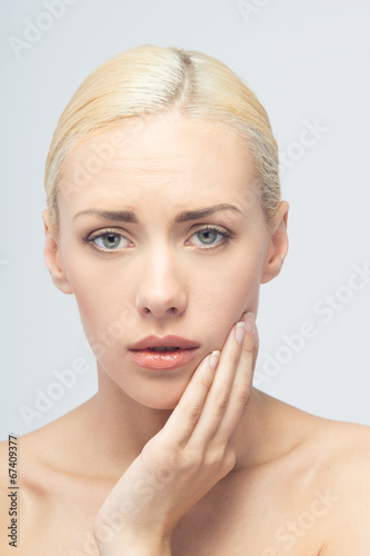 Photo: Pain concept. Young woman with touching her throat and head Pain concept. Young woman with touching her throat and head