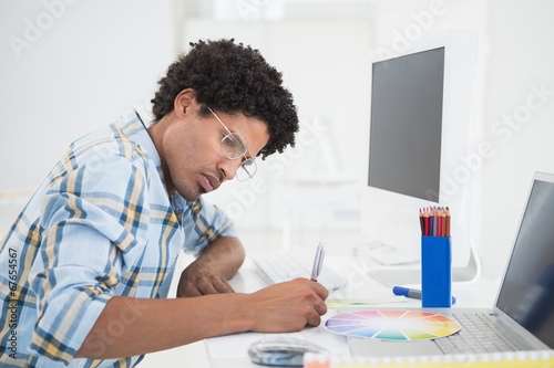Photo: Young designer working at his desk Young designer working at his desk