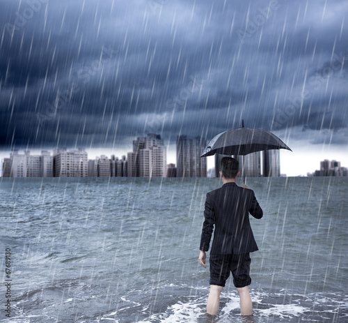 Photo: business man holding an umbrella and standing with cloudburst business man holding an umbrella and standing with cloudburst