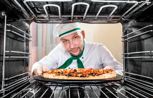 Photo: Chef cooking pizza in the oven. Chef cooking pizza in the oven.