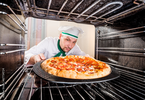 Photo: Chef cooking pizza in the oven. Chef cooking pizza in the oven.