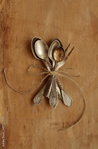 Photo: Bunch of vintage tea spoons and lemon fork tied up with bow Bunch of vintage tea spoons and lemon fork tied up with bow