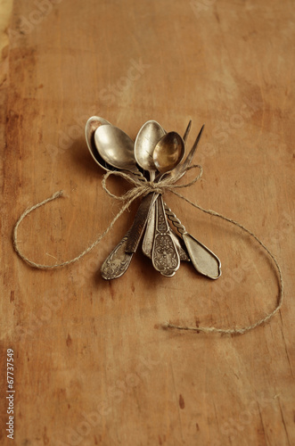 Photo: Bunch of vintage teaspoons and lemon fork tied up with bow Bunch of vintage teaspoons and lemon fork tied up with bow
