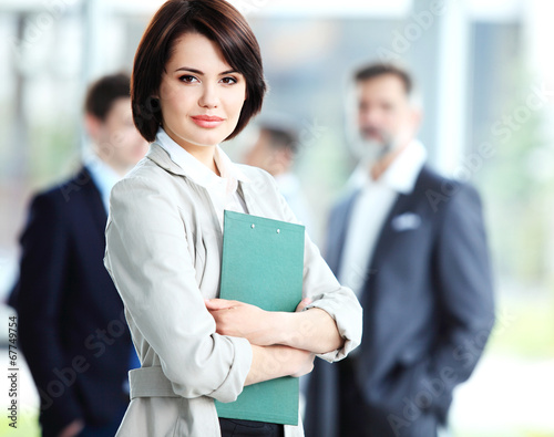 Photo: Businesswoman with her staff, people group in background Businesswoman with her staff, people group in background