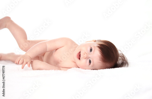 Photo: Happy little baby smiling while lying in bed Happy little baby smiling while lying in bed
