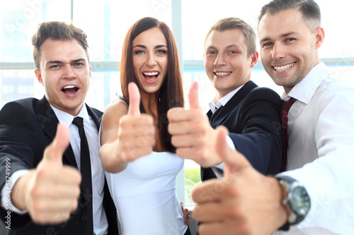 Photo: Successful young business people showing thumbs up sign Successful young business people showing thumbs up sign