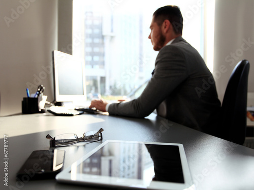 Photo: Silhouette of businessman using laptop in office Silhouette of businessman using laptop in office